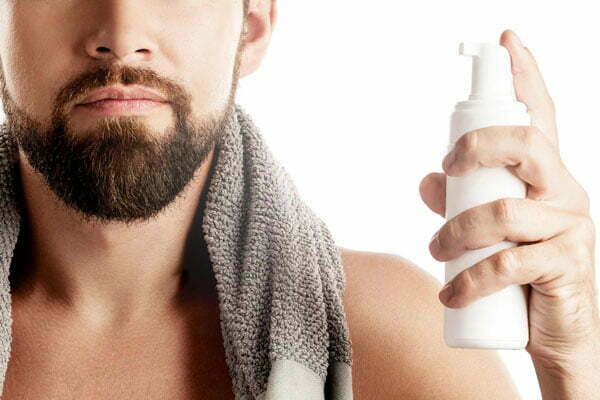 Mano sujetando un envase espumador de limpiador facial Mano sujetando un envase espumador de limpiador facial